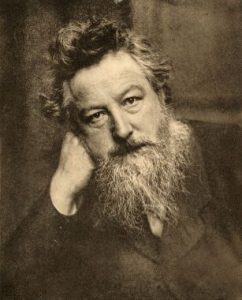 Photo de William Morris dans la cinquantaine : un homme sévère avec une barbe sauvage et une chevelure abondante. De plus, il a la tête appuyée sur sa main droite.