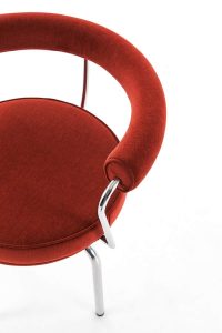 The Siège Pivotant, Designed by Charlotte Perriand in 1927: A red-cushioned chair with skinny metal arms and legs