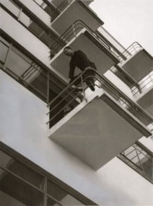 A young László Moholy-Nagy oh the Bauhaus balconies in Dessau, 1927: Photo of a man standing on a balcony. 
