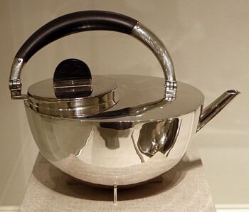 Tea pot, in silver and ebony (1924): a semi-circle pot with a dark handle and a skinny spout. 