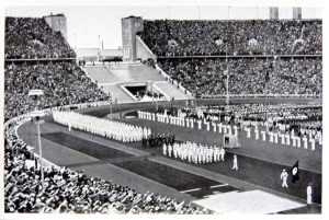 German Olympic team marching in the Berlin Olympic Stadium (1936): Black and white photo of the stadium. 