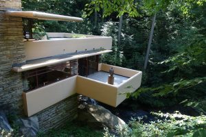 Fallingwater House, Frank Lloyd Wright’s own favorite piece. Pennsylvania, 1935.: A sand-colored building built into the vegetation with uneven platforms sticking out. 