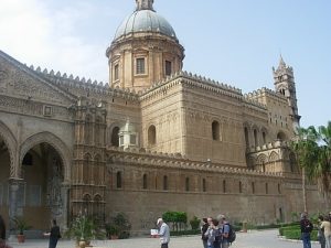 The Cathedral of Palermo is an architectural complex in Palermo (Sicily, Italy): An ornate stone structure with a central dome and various rectangular additions. 
