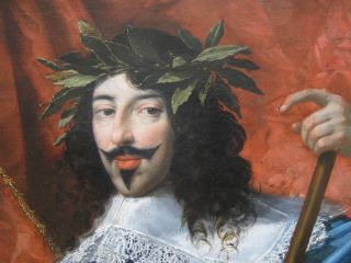 Luís XIII entra em França e Navarra. Usa uma coroa de plantas, está vestido com um fato branco, tem a pele clara e o cabelo escuro. Além disso, está de pé em frente a um fundo vermelho. 