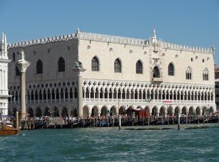 Palazzo Ducale, Venezia, Italia. Una grande struttura bianca, rettangolare con 2 file di archi che rivestono il fondo e finestre ad arco che si ergono lungo la parte superiore della struttura. 