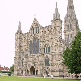 Catedral de Salisbury em estilo gótico.  Uma grande estrutura de pedra com várias janelas em arco e ornamentação. Além disso, existem três pontos ao longo da frente do edifício.