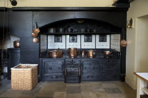 Interior de estilo industrial. Exemplo de cozinha estilo Industrial, com armários pretos e louças douradas.