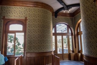 Interior do Villino Florio em Palermo em estilo Arte Nova italiano. Interior em madeira clara e grandes janelas em arco. Além disso, há papel de parede verde claro.