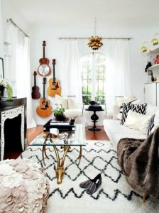 Interni Boho - Mix di ottone, coperte, cuscini e tappeti con texture morbida, chitarre appese al muro e contrasti bianchi e neri. 