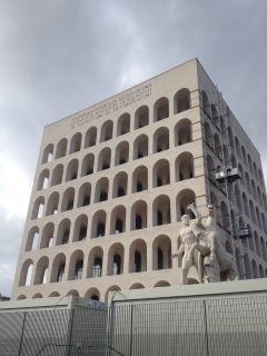Palazzo della Civiltà Italiana. Grande edificio in pietra bianca con ritagli su ogni facciata a forma di arco. 