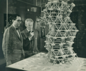 Louis Kahn next to another man, both looking at one of his designs.