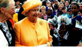 Queen Elizabeth II and Eileen Gray at the 2002 London Youth Games: the queen is seen in a bright yellow outfit, while gray is in a much more muted ensamble. 