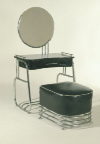 Vanity con specchio: per la maggior parte è sottile, in metallo, ma il cuscino della sedia e la scrivania sono neri. Lo specchio è di forma circolare. 