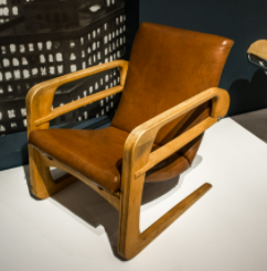 Sedia da aereo - Kem Weber: Una sedia marrone con cuscini marroni. 