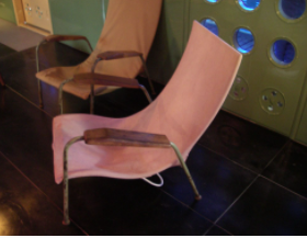 Maison Tropicale interior: Two curved, pink chairs with skinny arms and legs. Additionally, the armrests are made of a skinny piece of wood. 