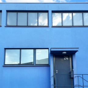 Mart Stam Haus à Stuttgart : Un bâtiment bleu clair avec des fenêtres rectangulaires à bordure noire sur deux rangées distinctes.