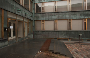 Casa della Cultura: Una foto del lato della struttura con finestre a bordi chiari e rivestimenti grigio-verde scuro. 