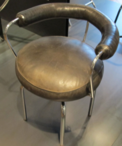 Siège pivotant (1927), by Charlotte Perriand,. Musée des Arts Décoratifs, Paris: A skinny metal chair with brassy cushions