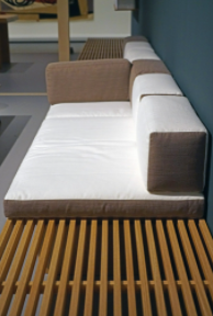 Conception Charlotte Perriand (1954) a bamboo bench with white, and tan cushions. 