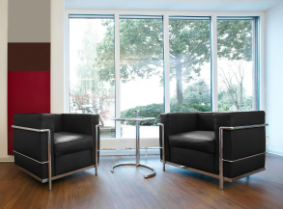 LC2 Armchair: Two black-cushioned armchairs with silver hardware. 