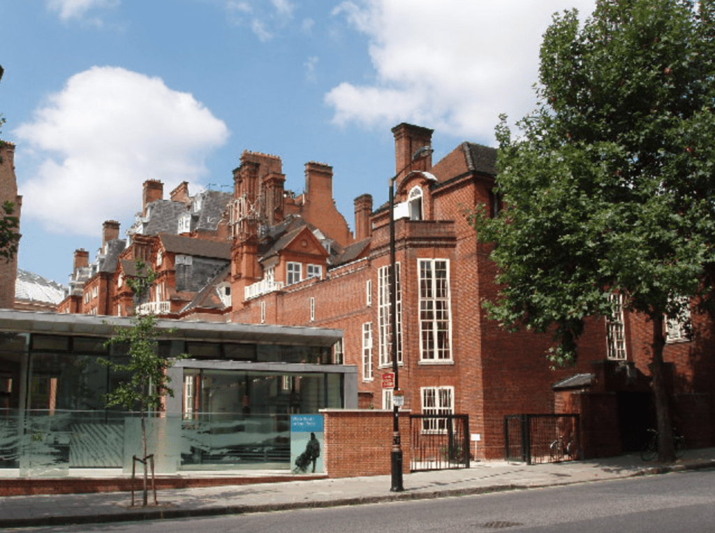 Lowther Lodge, headquarters of the Royal Geographical Society, designed by Richard Norman Shaw in 1873-1875. A large medium-colored brick structure with large white windows. 