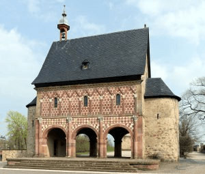 Lorsch Abbey: A Carolingian Monastery with red and white bricks, three arches along the bottom and a black roof. 