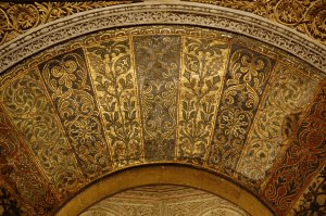 The mosaics in the voussoirs of the mihrab arch, which are gold and composed of leaf-like flourishes.
