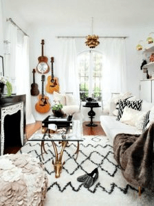 Boho Style interior- Brass luxe mix, photo with textured rugs, pillows and blankets, guitars on the walls and white and black contrasts. 