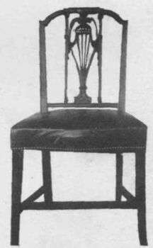 A Sheraton style chair with rectangular back. A black wood chair with a fluffy cushion. Photo is in black and white. 

