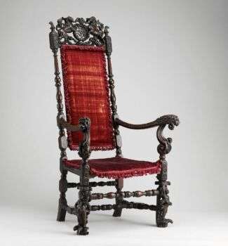 A walnut armchair with ornate flourishes and a modern velvet cushion.  