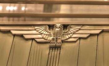 Art Deco Owl in the foreground, realized in golden lucid metal.