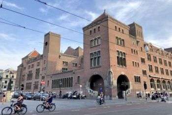 Beurs van Berlage, Binnenstad, Amsterdam, Noord-Holland, Nederland: A photo of the red-brick structure with tourists along the front ridding bikes. 