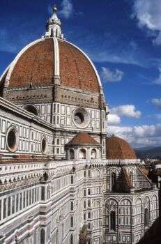 La Cupola di Filippo Brunelleschi vista dal Campanile di Giotto: una grande struttura chiara con tetti a cupola rosso scuro e marrone. 