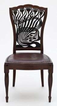 Chair with an abstract back, possibly depicting flowers or plants. 