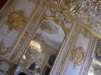 A sideways, closeup of the white wall with gold accents in the Chamber of the Prince, in Hôtel de Soubise. 