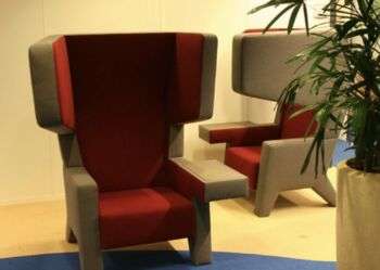Cocoon Chair. Esempio di sedia in design moderno con cuscini interni in rosso e struttura esterna in grigio. 