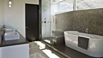 Foto del design di un bagno contemporaneo, con una grande vasca bianca poggiata lungo un muro decorato con fantasia astratta. 