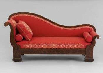 A mahogany lounge chair with a bright red cushion.