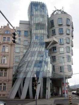 Frank Gehry's Dancing House - Prague, Czech Republic. the building appears bended on one side, as if something hit it and left it damaged. 