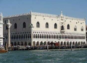 Doge's Palace, in Venice, which is a large white, rectangular structure with 2 rows of arches that line the bottom and arched windows spread along the top of the structure. 