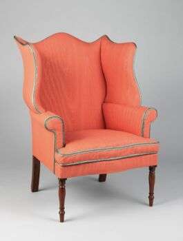 A bright orange easy chair with mahogany legs. 