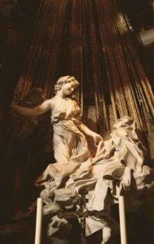 Ecstasy of Saint Teresa stature: a white stone piece of art surrounded by gilded bronze.