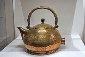 Electric kettle by Peter Behrens (museum of decorative arts, Paris): A brass tea kettle with a circular handle. 