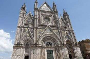 Facade of Orvieto Cathedral: A large, ornate grey stone structure with various arches and triangular points. 