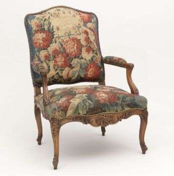 Armchair with medium-wood legs and arms and flower-patterned cushions. 