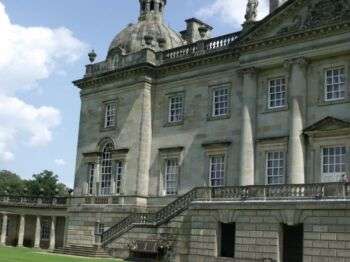 The west front of Houghton Hall, which is a large grey-stone building. 