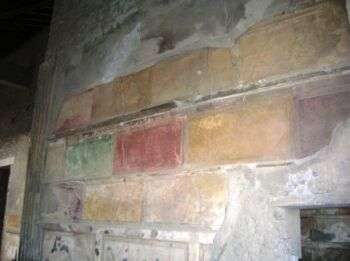 House of Sallust -Pompeii. Wall laid with colored marble stone (yellows, reds, and greens occupy most of the photo). 
