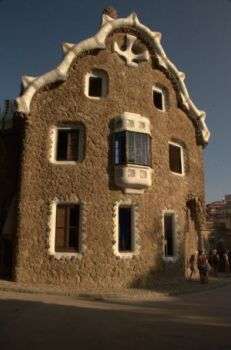 Houses in Park Güell designed by Antoni Gaudi, Barcelona, Spain: A brown house with three floors and windows of various sizes. 