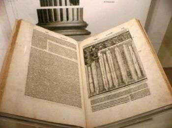 A photo of De Architectura opened up, with writing on the left and a drawing of columns on the right. 