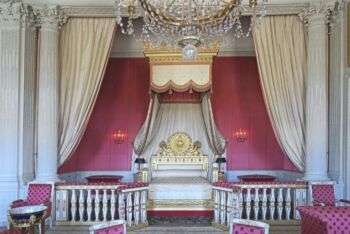 Le Grand Trianon (Versailles): A grand bedroom with pink walls, pink cushioned furniture and light colored accents.